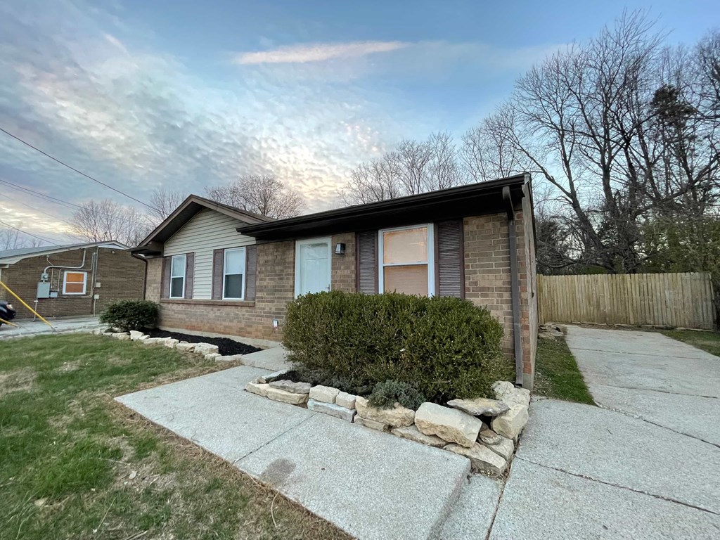 a small brick house with a sidewalk in front of it