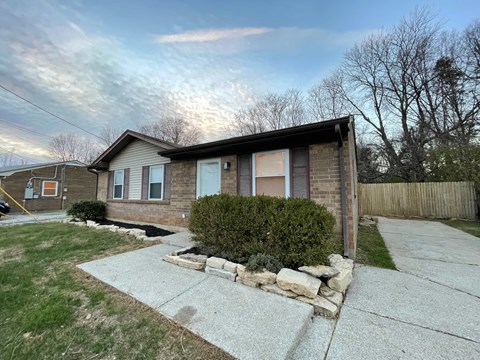 a small brick house with a sidewalk in front of it