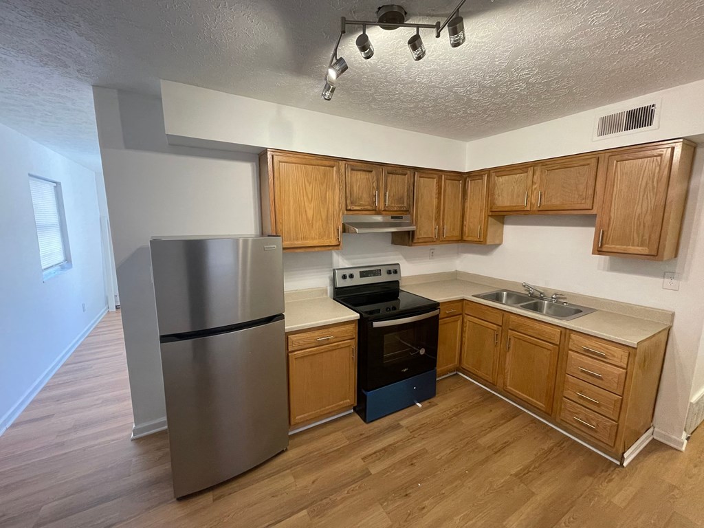 an empty kitchen with wooden cabinets and a stainless steel refrigerator