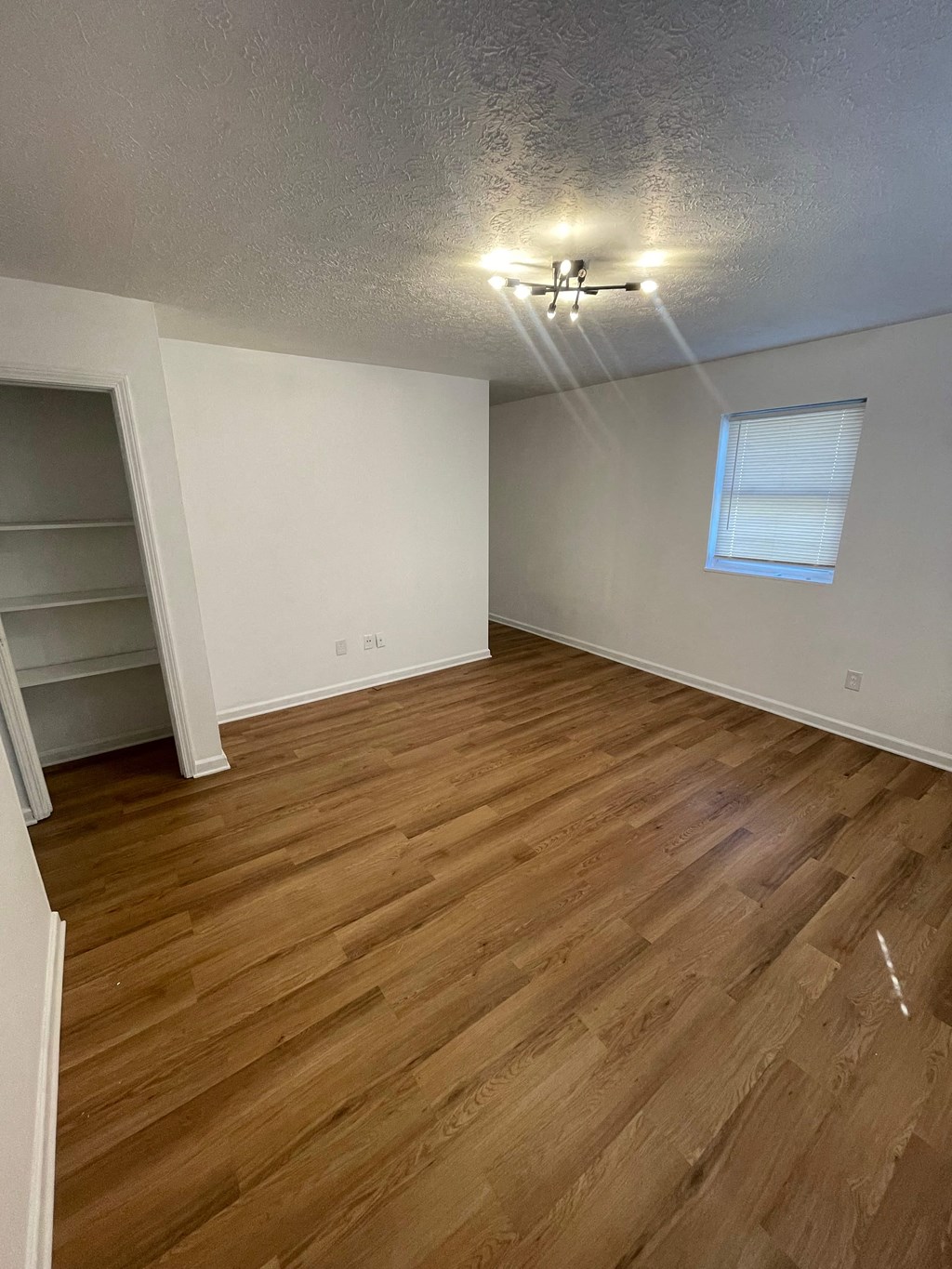 an empty living room with wood flooring and a window