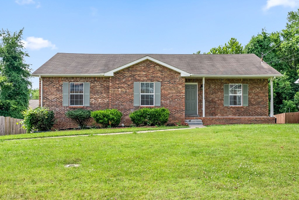 a small brick house with a lawn in front of it