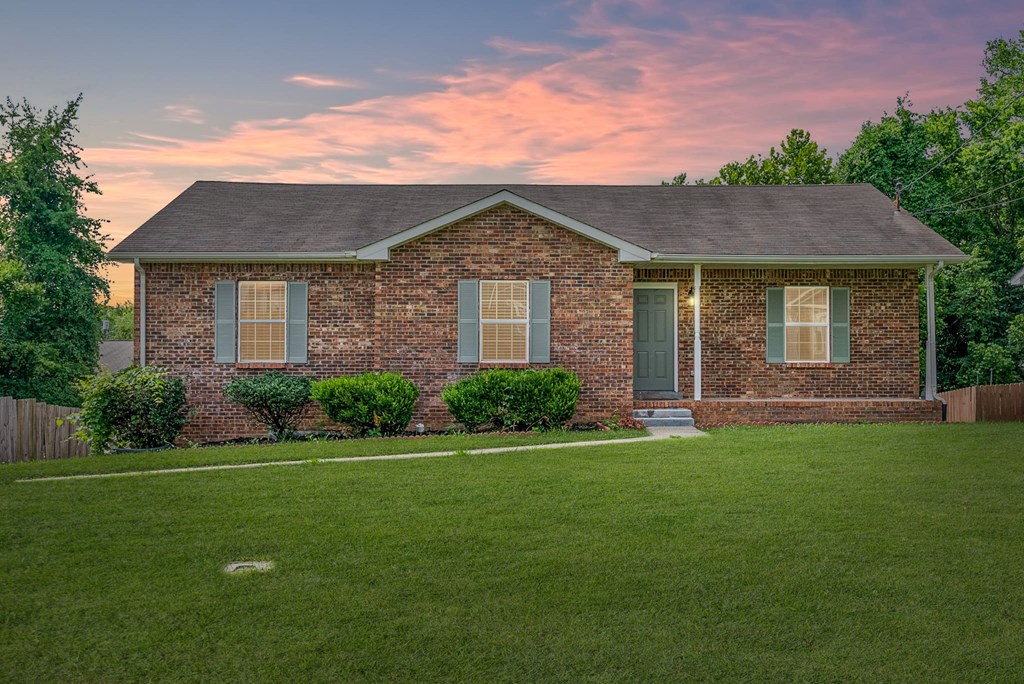 a small brick house with a lawn in front of it