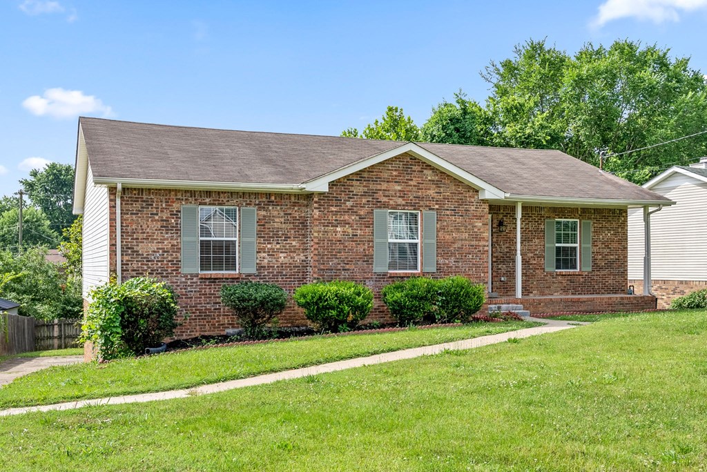 a small brick house with a lawn and a sidewalk