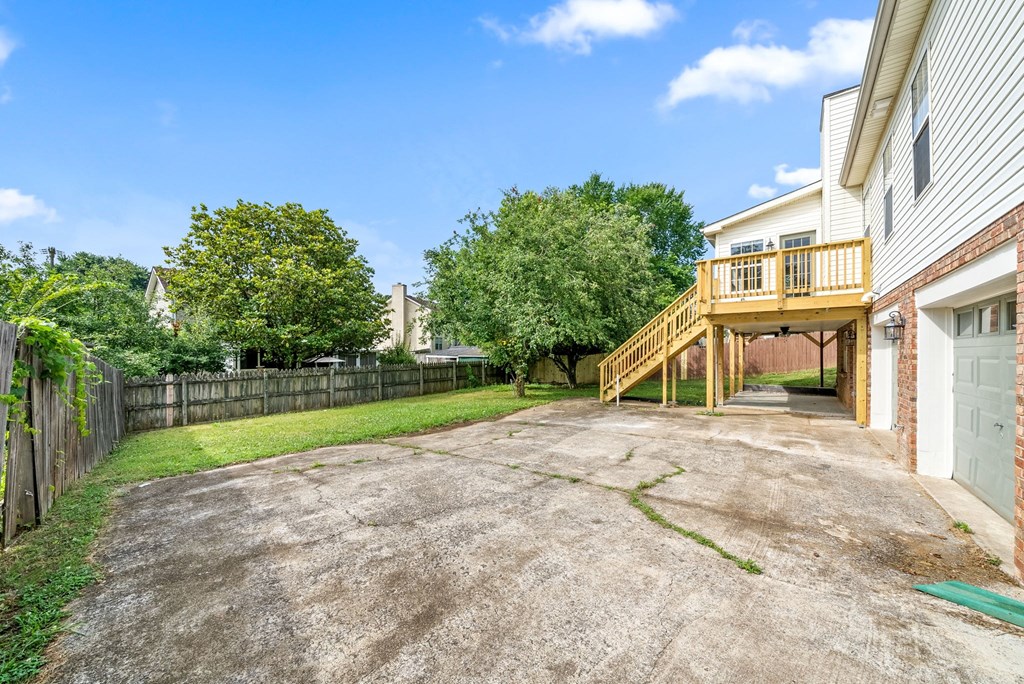 the backyard of a house with a deck and a driveway