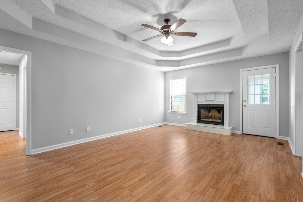 an empty living room with a fireplace and a ceiling fan
