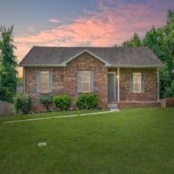 a small brick house with a lawn in front of it