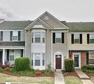 A two-story house with a front porch and a small front yard.