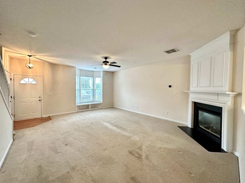 A living room with a fireplace and a ceiling fan.