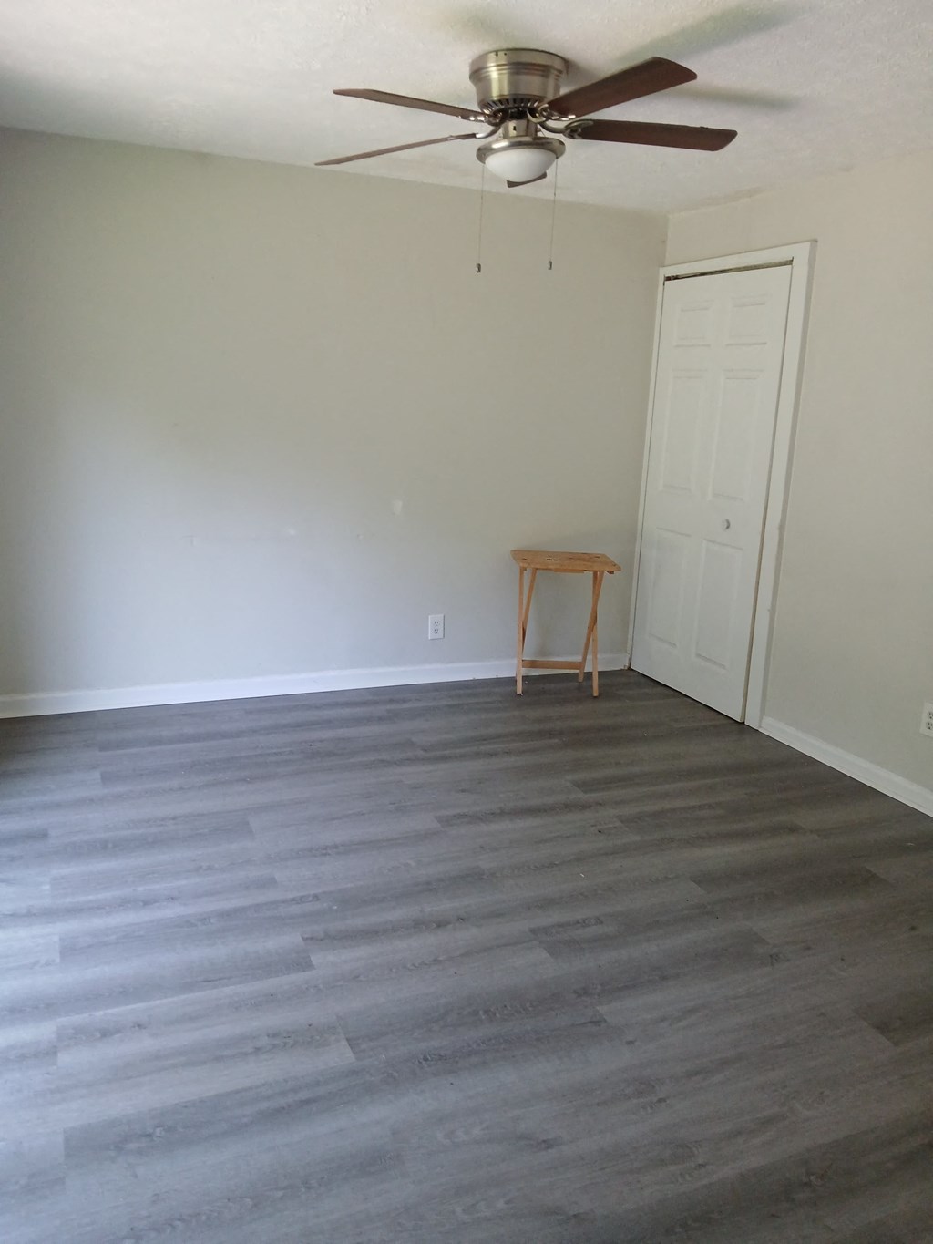 an empty living room with wood floors and a ceiling fan