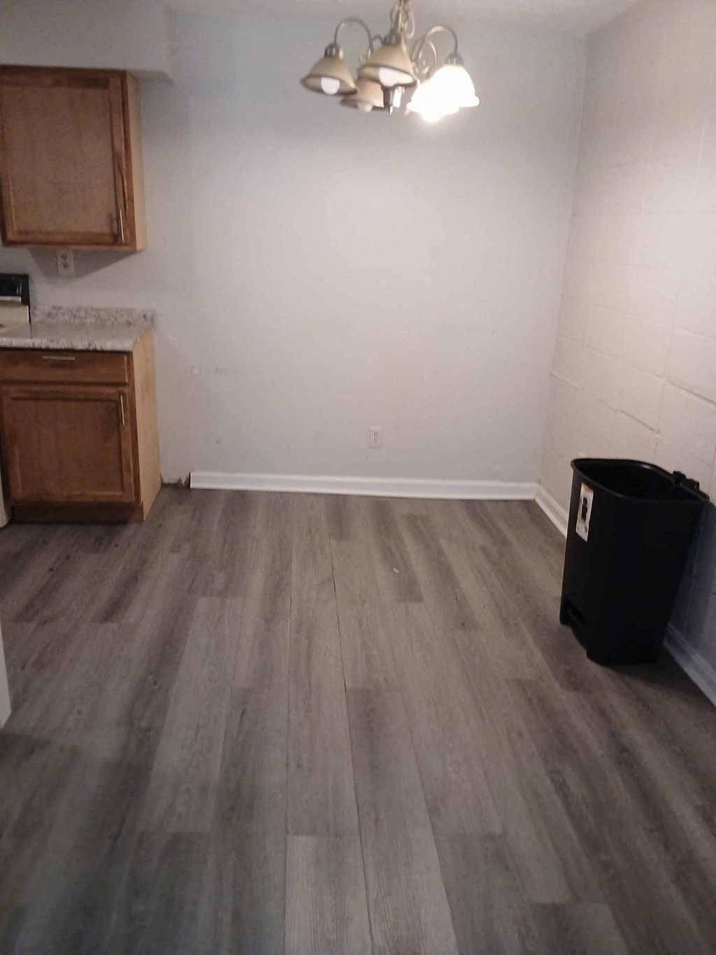 an empty room with wooden floors and a trash can