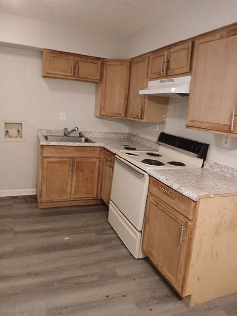 an empty kitchen with wooden cabinets and white appliances
