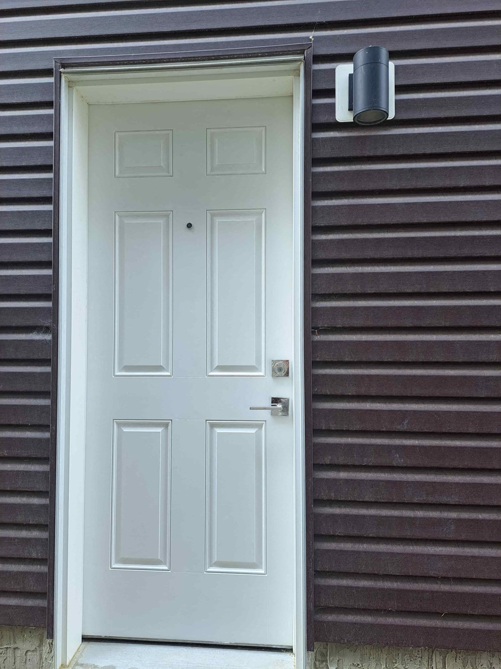 a white door on the side of a brown siding