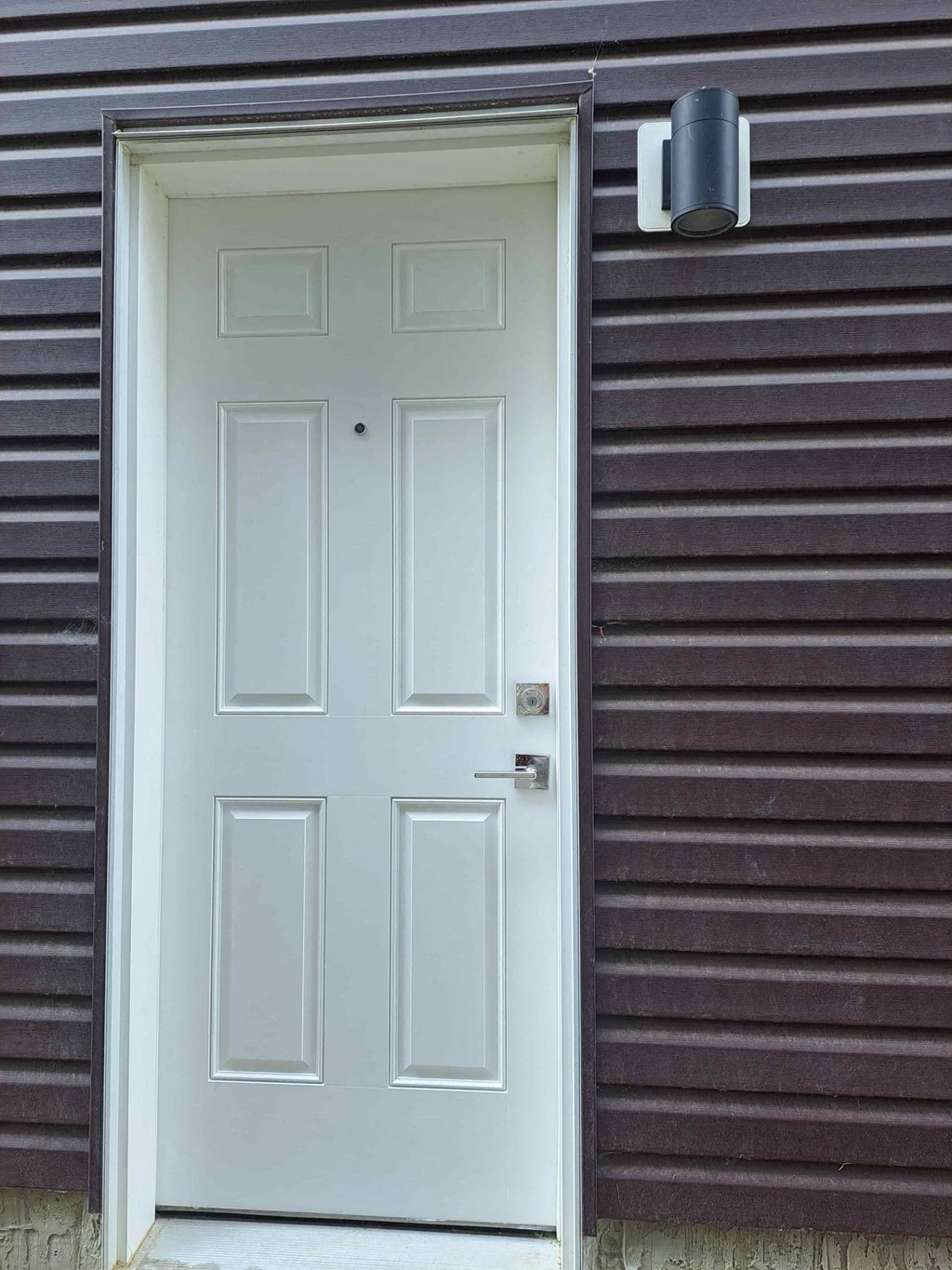 a white door on the side of a brown siding