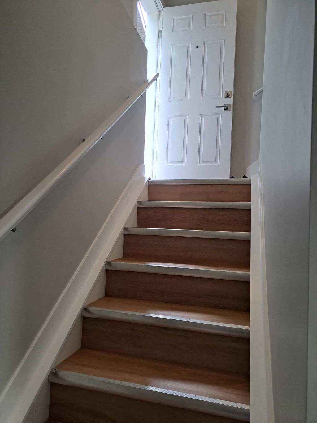 the stairway up to the second floor of a house with a white door
