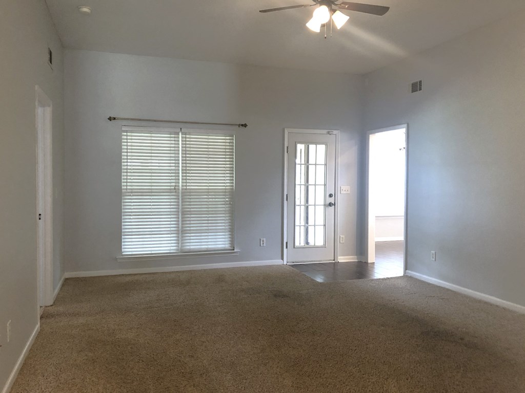 an empty living room with white walls and a ceiling fan