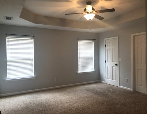 a living room with a ceiling fan and two windows