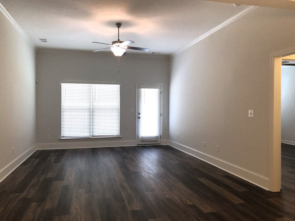 an empty living room with wood floors and a ceiling fan