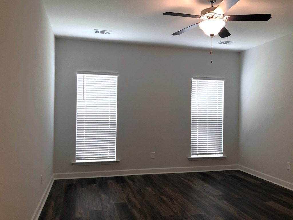 a living room with two windows and a ceiling fan