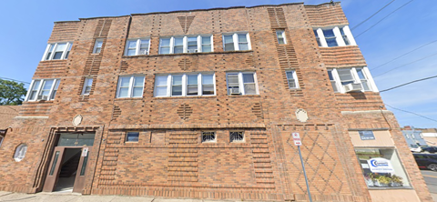 A red brick building with a white sign on the right side.