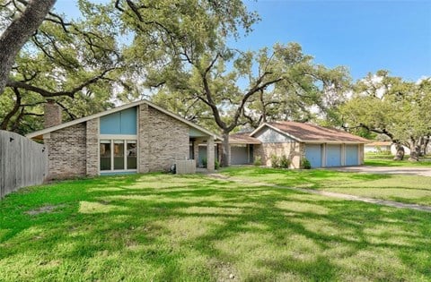 a house with a yard and trees in front of it