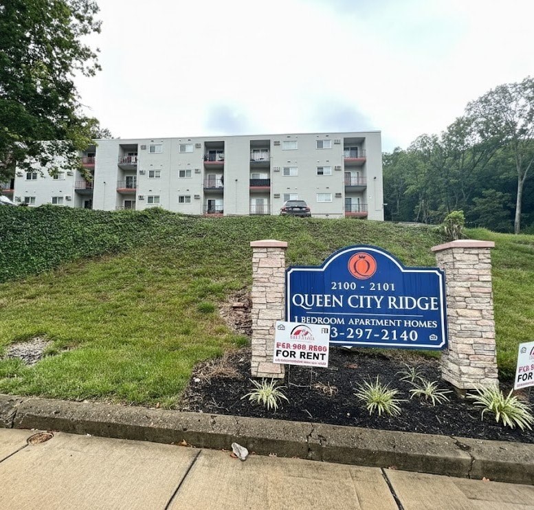 A sign for Queen City Ridge 1 Bedroom Apartment Homes is in front of a building.