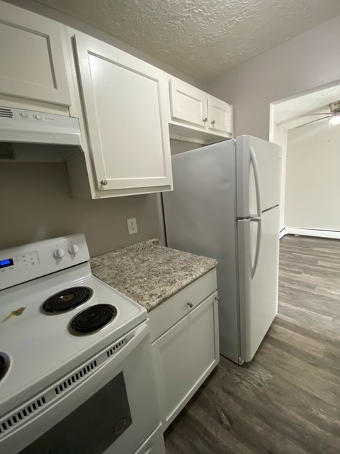 A kitchen with a white stove top oven and a white refrigerator.