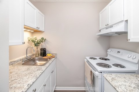A kitchen with a white stove and a sink.