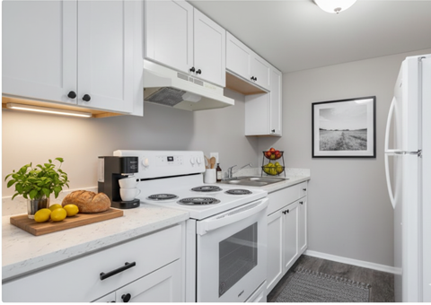 A white kitchen with a refrigerator on the right.