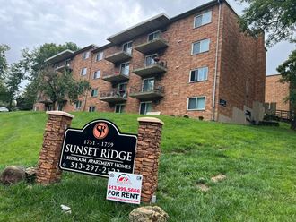 an apartment building with a sunset ridge sign in the grass