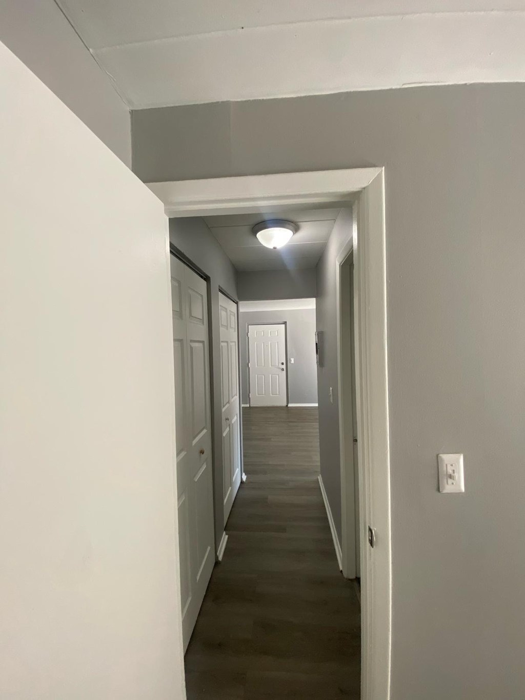 A long hallway with white walls and a light on.
