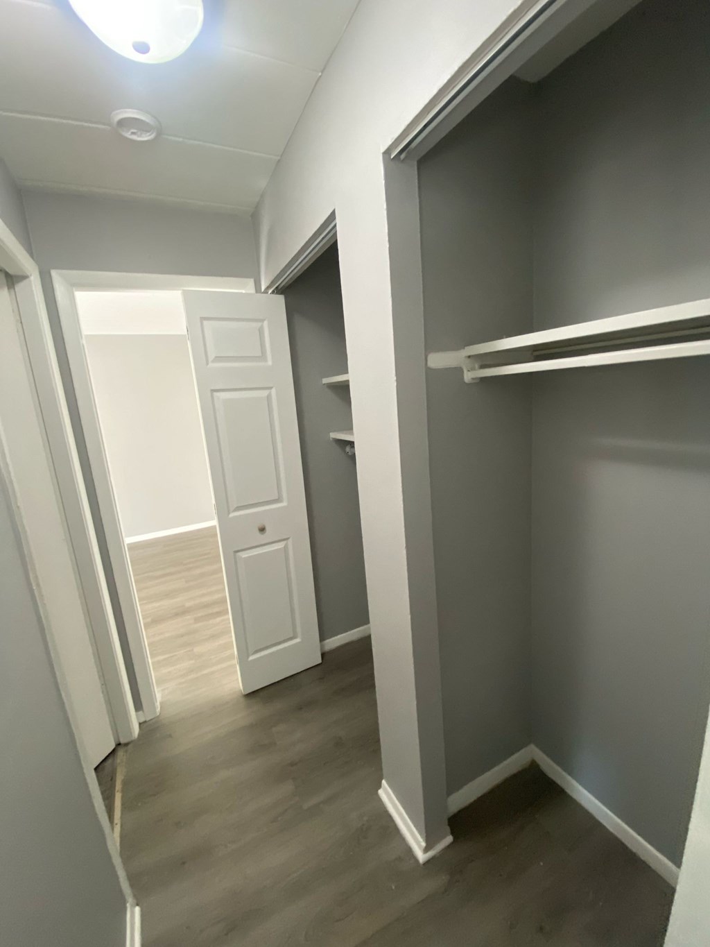 A white door is open to a hallway with a shelf.