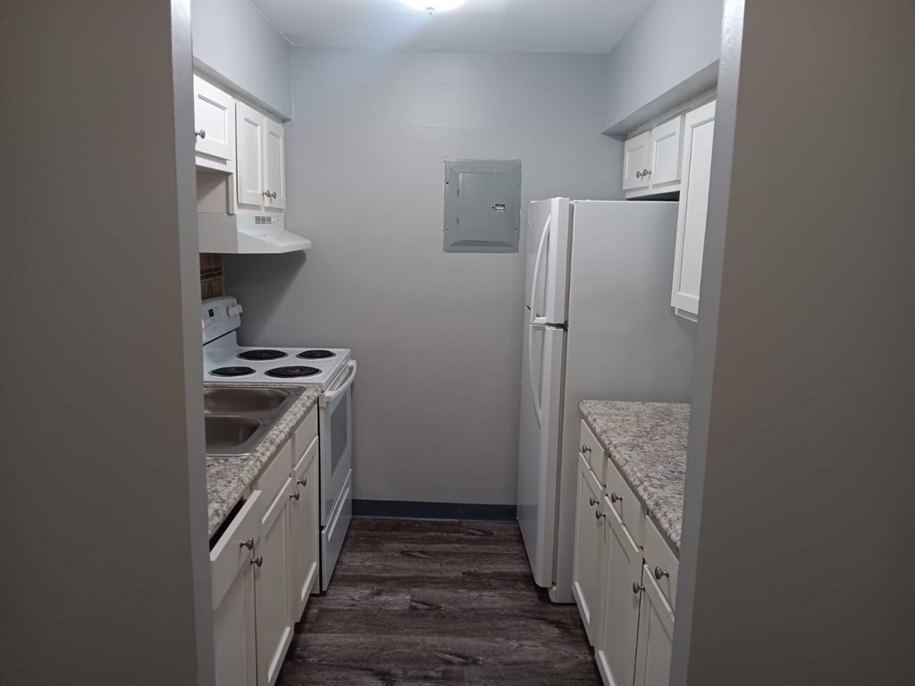 A kitchen with white cabinets and a refrigerator.