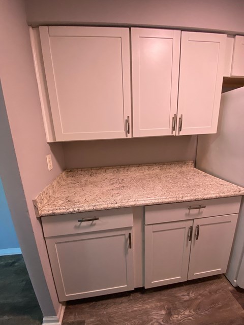 A kitchen with white cabinets and a granite countertop.