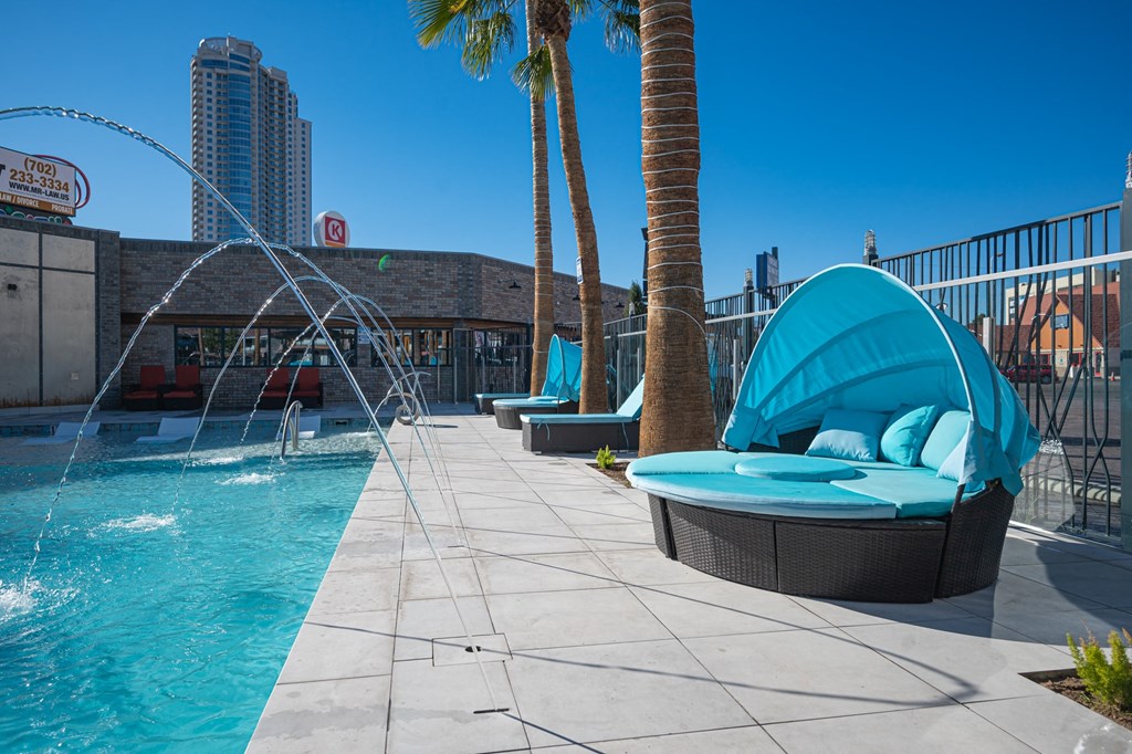 a swimming pool with a water fountain and chairs on a rooftop
