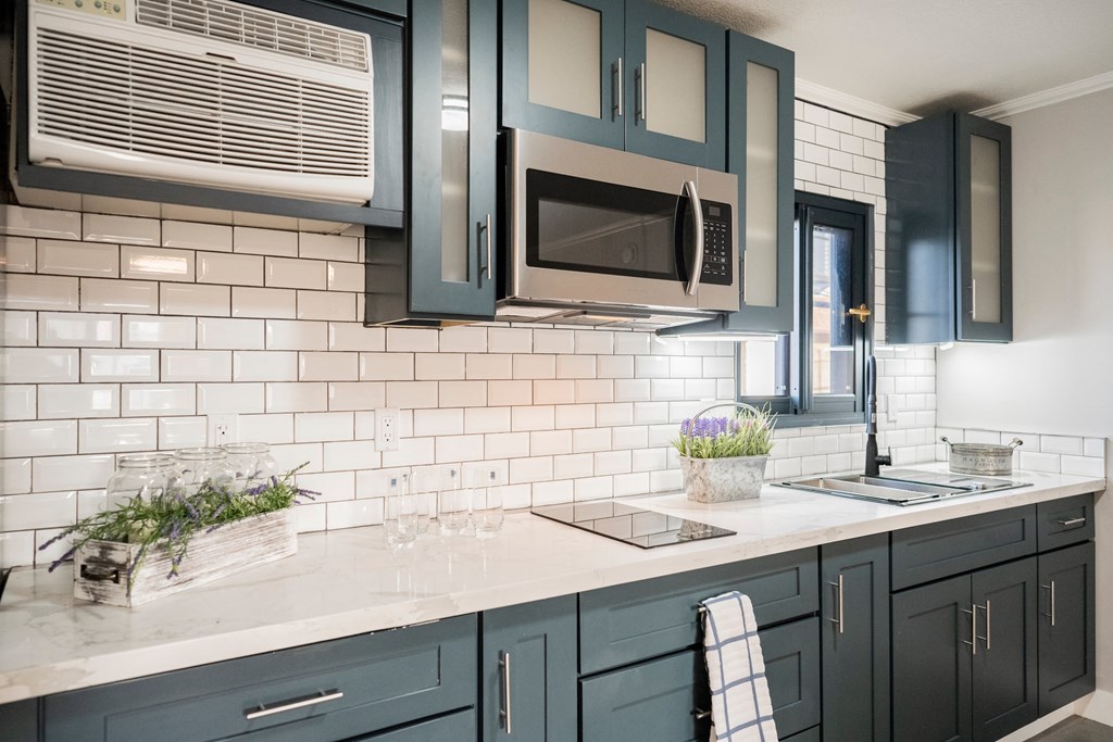 a kitchen with blue cabinets and a white counter top with a sink and a microwave