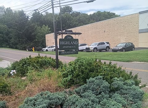 A sign for Highland Apartments stands in front of a building.