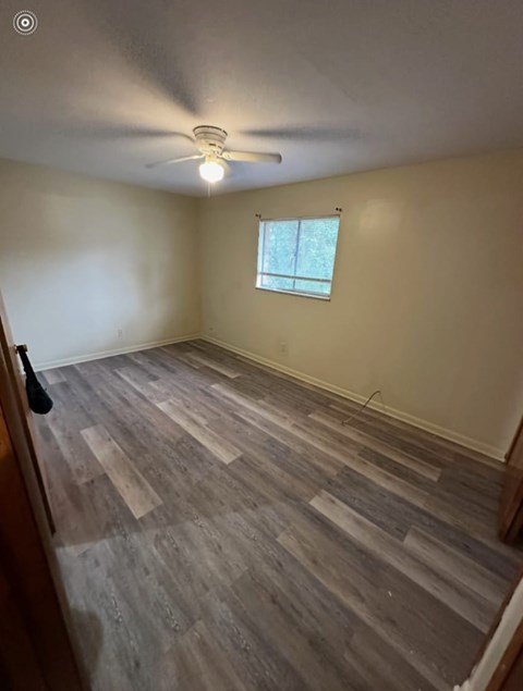 A room with wooden flooring and a window.