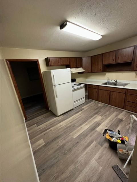 A kitchen with a white fridge and wooden cabinets.