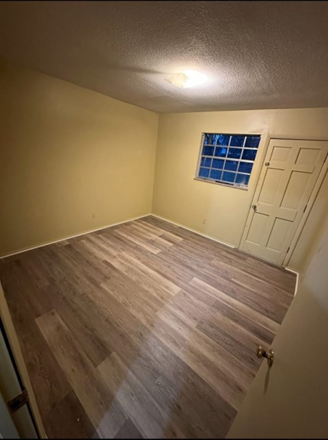 A room with wooden flooring and a window with bars on it.