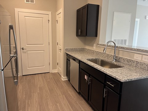 A kitchen with black cabinets and a white door.