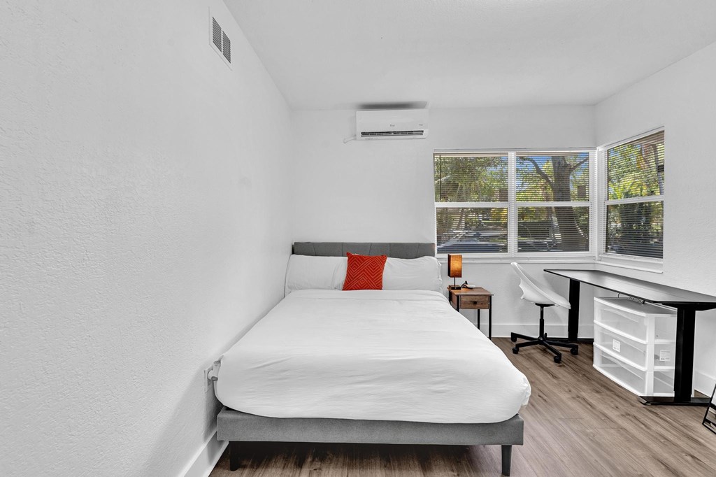 A bedroom with a bed, desk, and chair.