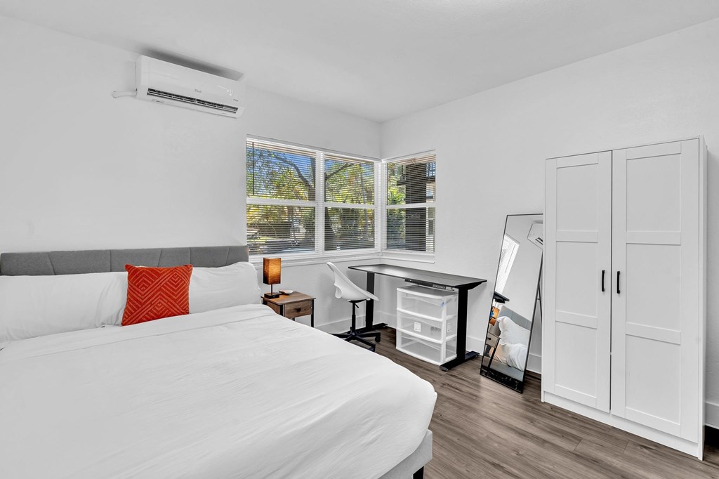 A bedroom with a large bed and a desk with a chair.