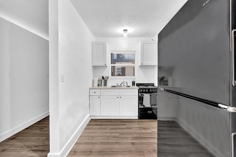 A kitchen with white cabinets and a black refrigerator.