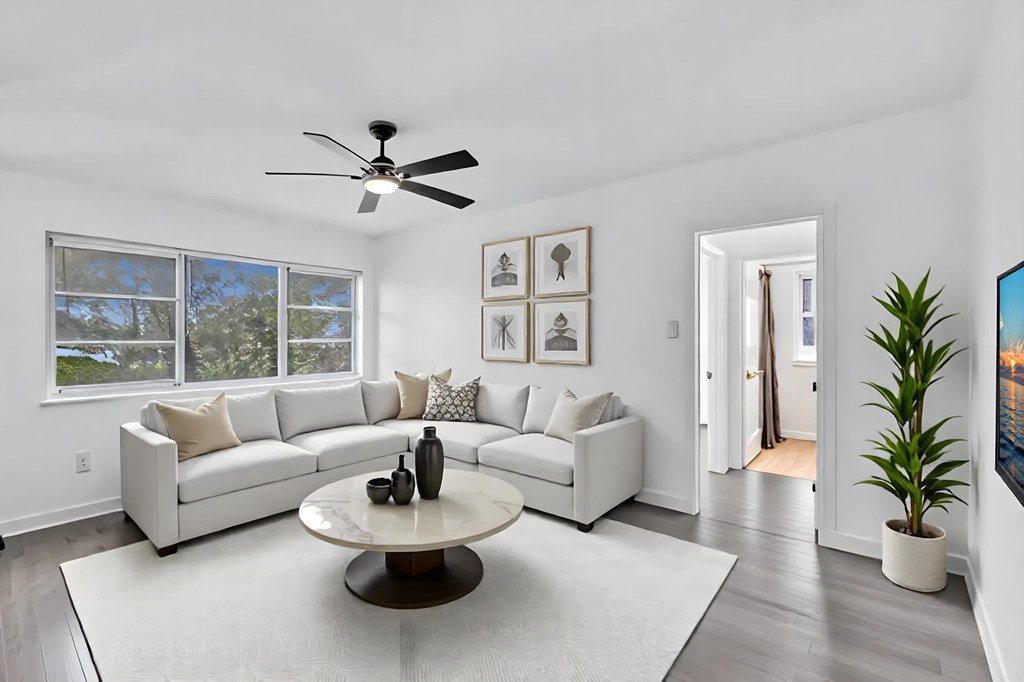A living room with a white couch, a coffee table, and a ceiling fan.