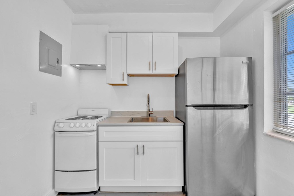 A white kitchen with a stove, sink, and refrigerator.