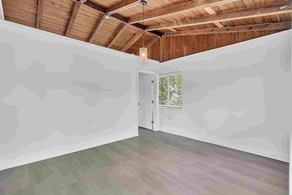 A room with a wooden ceiling and a door leading to a balcony.