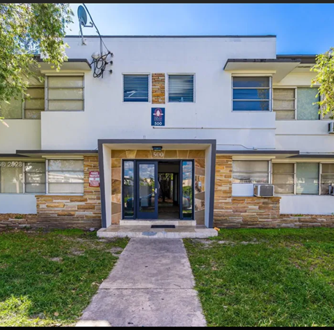 A white building with a brown door and windows.
