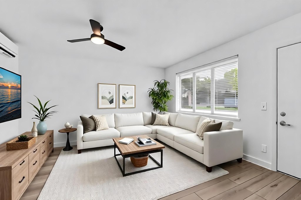 A living room with a white couch, a coffee table, and a ceiling fan.