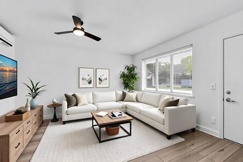 A living room with a white couch, a coffee table, and a ceiling fan.