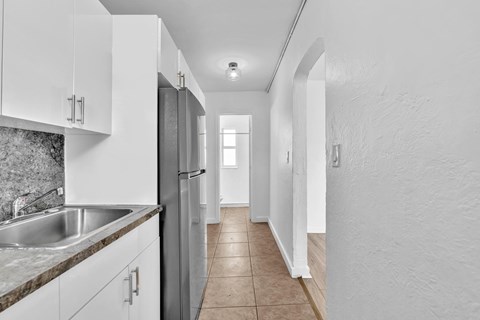 A kitchen with white cabinets and a stainless steel refrigerator.